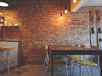 Interior of a fitted-out cafe with exposed brick, pendant lighting and timber tables.