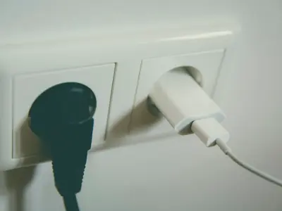 Two wall power outlets with a plug and a USB-style charger fitted in a home office.